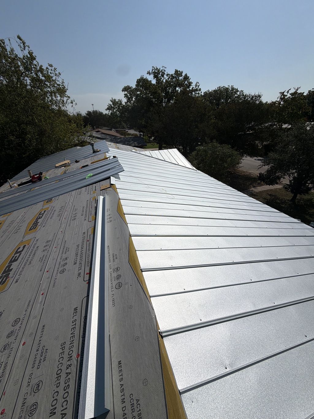 Standing seam metal roof panels being installed over synthetic underlayment in San Antonio