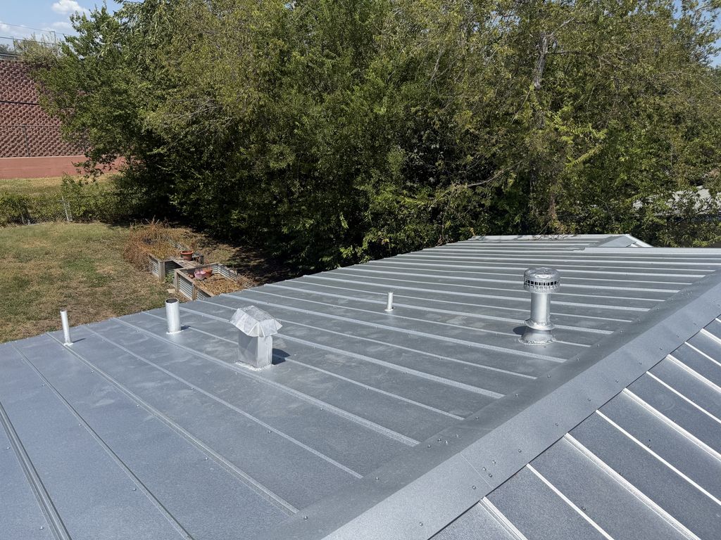 Completed galvalume standing seam metal roof with vent boots on a San Antonio home