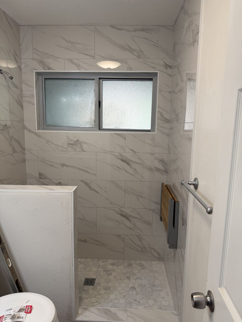 Finished walk-in tile shower after a tub-to-shower conversion in San Antonio, marble-look tile with hex mosaic floor